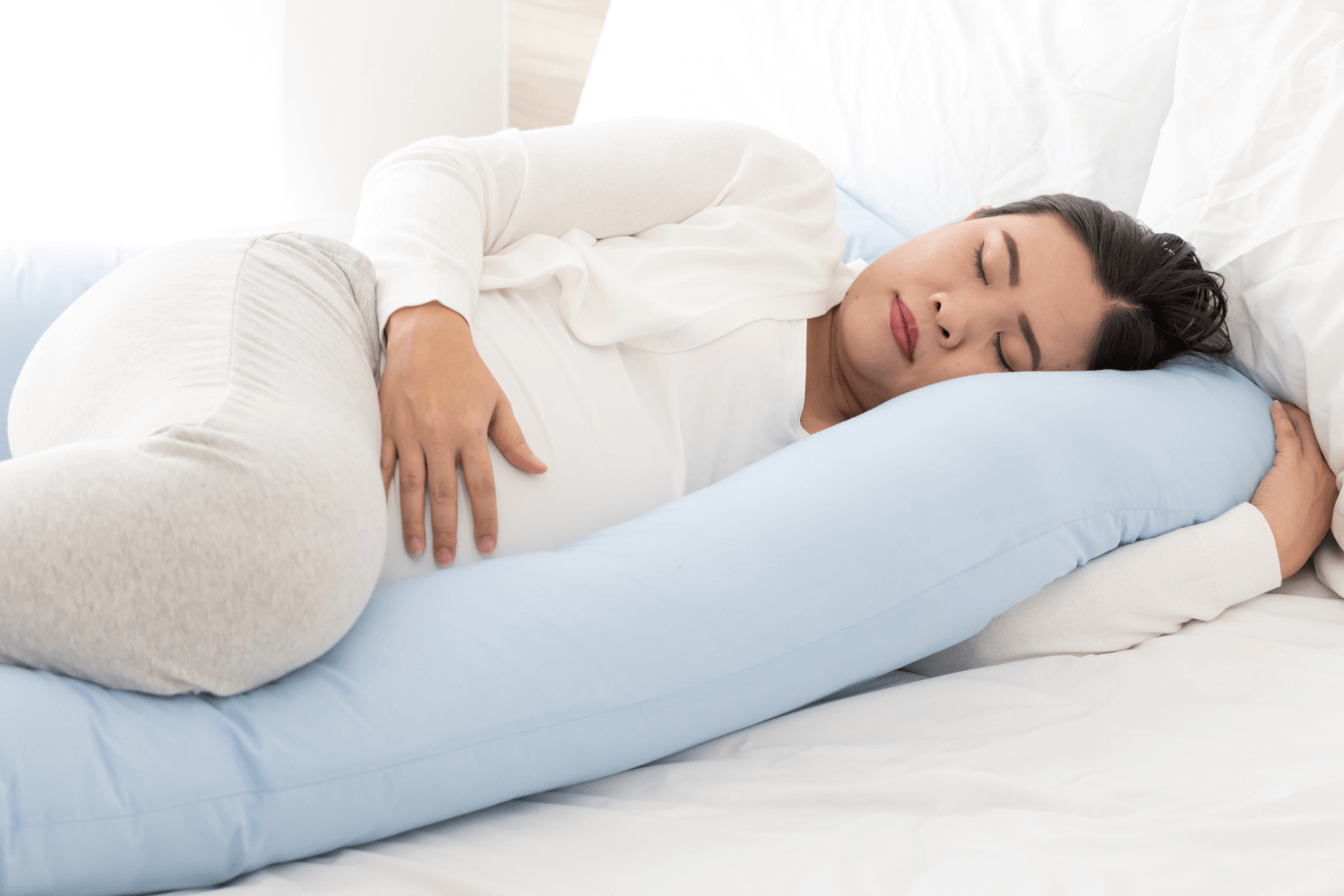 Pregnant woman resting on a pregnancy body pillow
