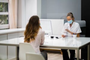 woman sitting at desk across from a healthcare worker