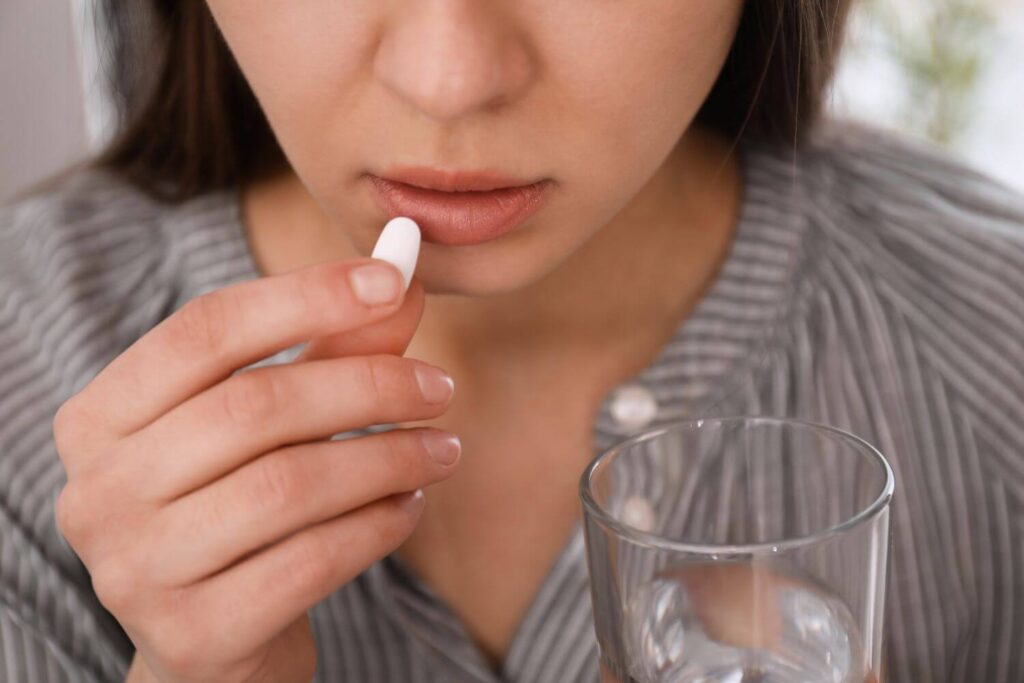 Woman holding a glass of water and an abortion pill to her mouth