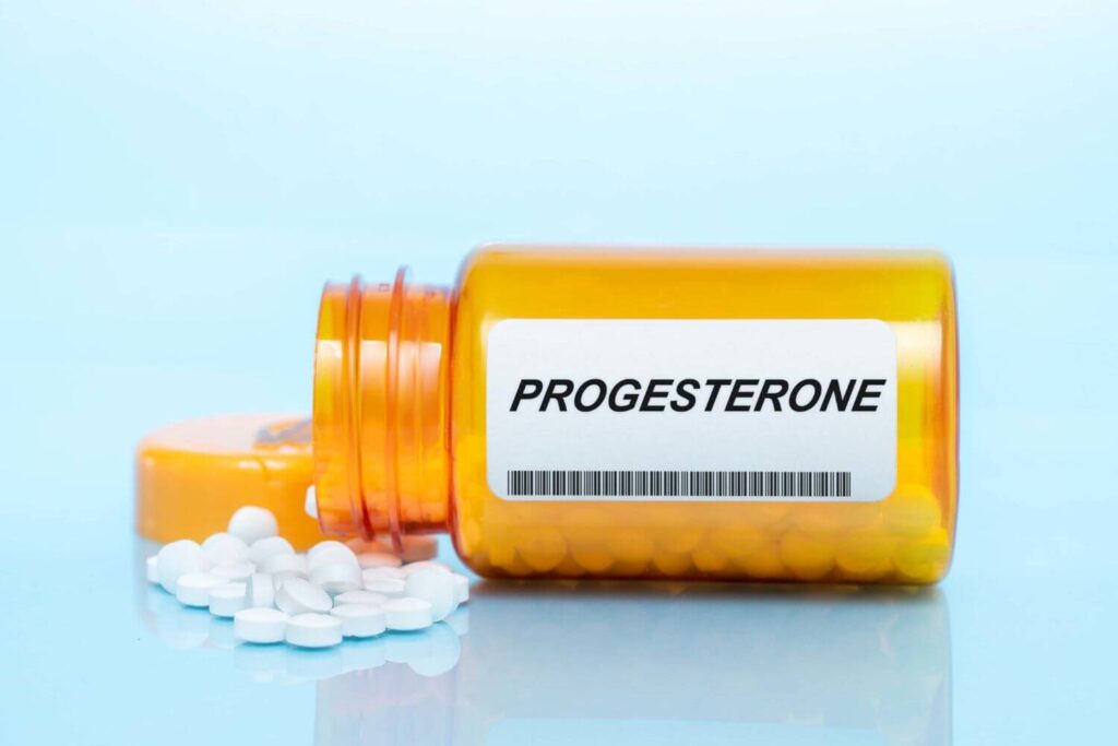 A bottle of progesterone pills is laying sideways, will small white pills coming out of the bottle
