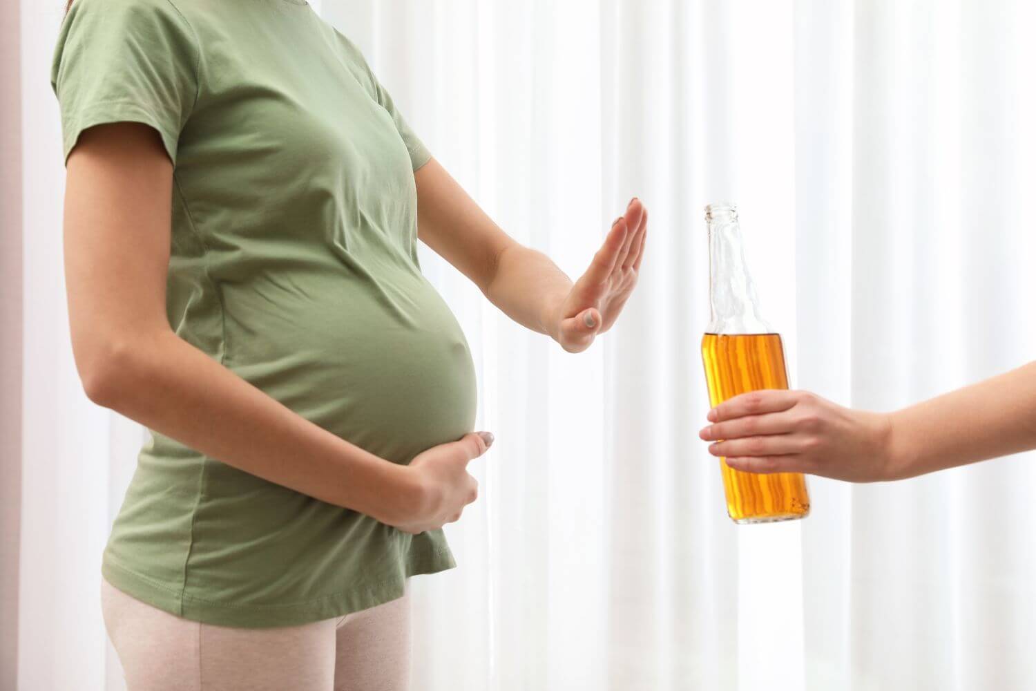 Pregnant woman putting her hand out to deny an alcoholic beverage that's being offered to her