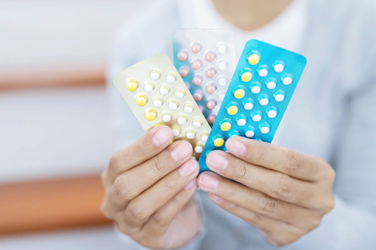 Woman holding 3 packages of contraceptive pills