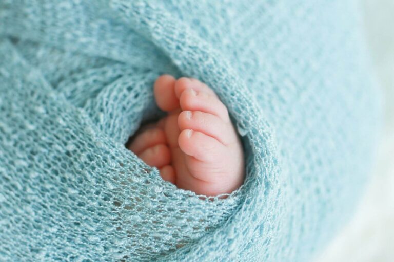 newborn baby toes wrapped in a blue blanket