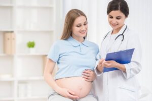 Pregnant woman looking at a clipboard that a doctor is holding while standing next to her