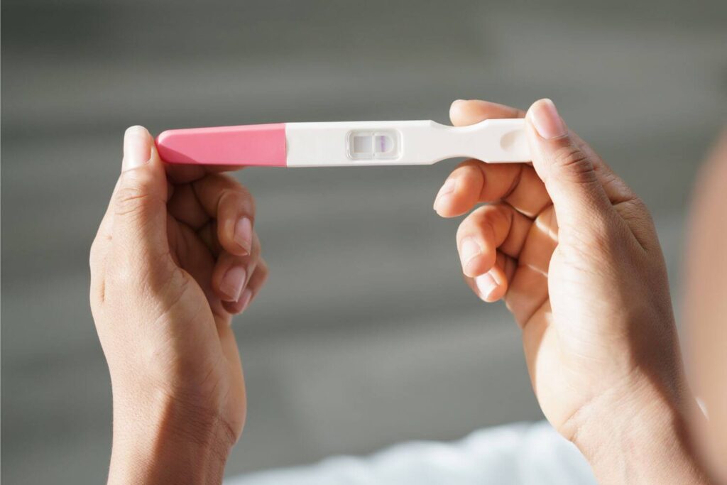 Two hands holding a pregnancy test reading a negative result