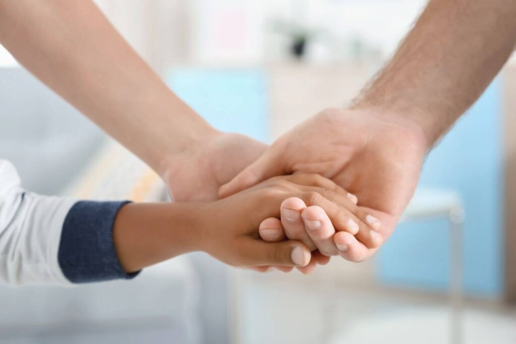 a mom, dad, and child have their hands placed together