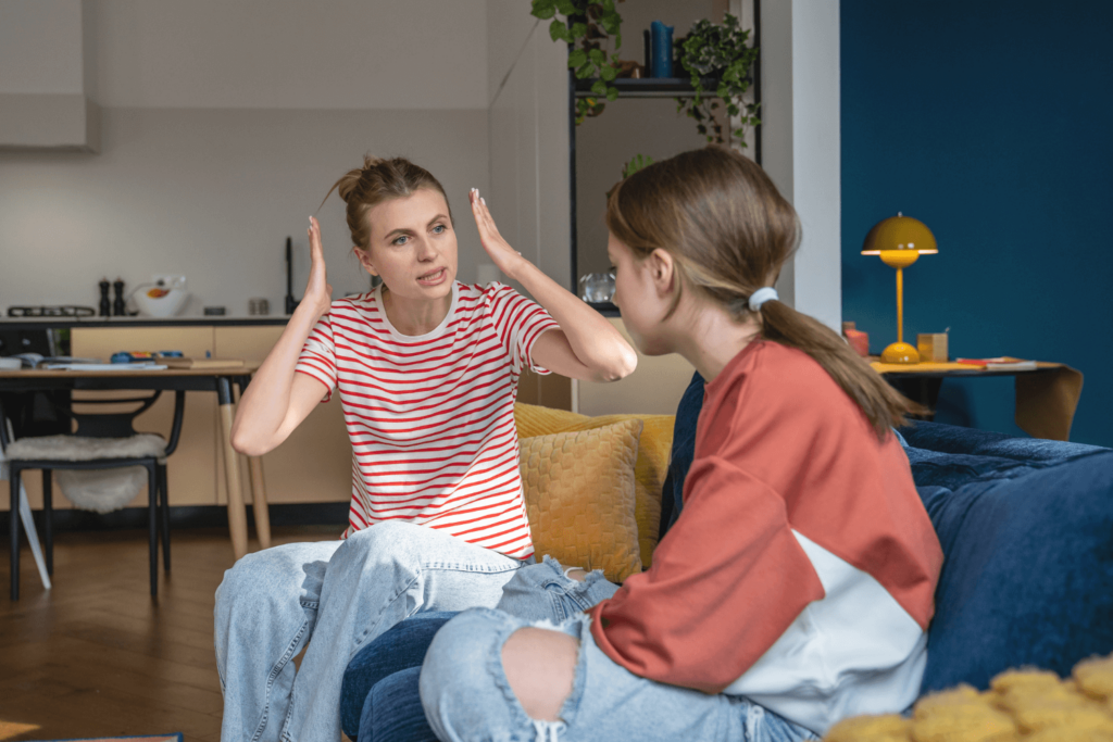 Frustrated mother has her hands up while talking to younger daughter