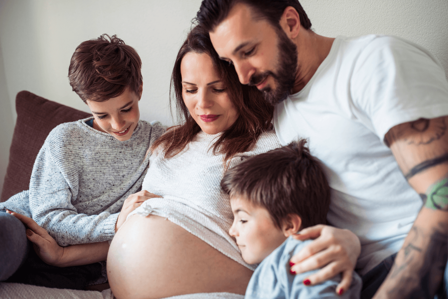 Pregnant mother embracing children and husband