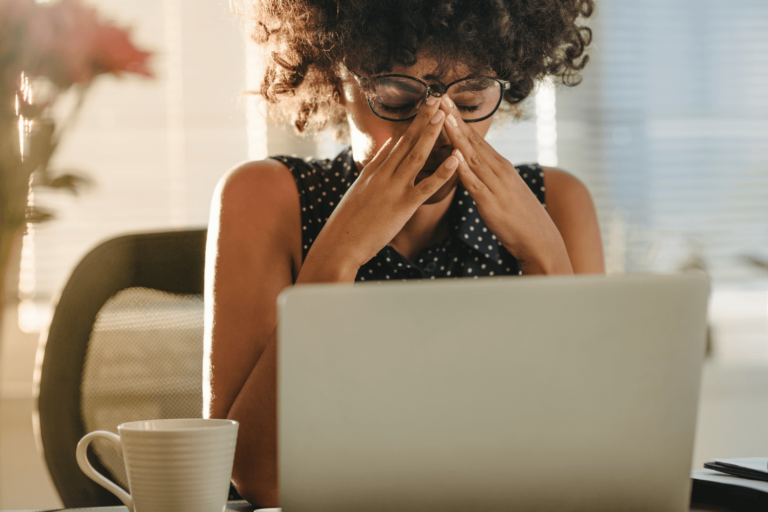 Stressed woman with her hands on her face while sitting at her computer