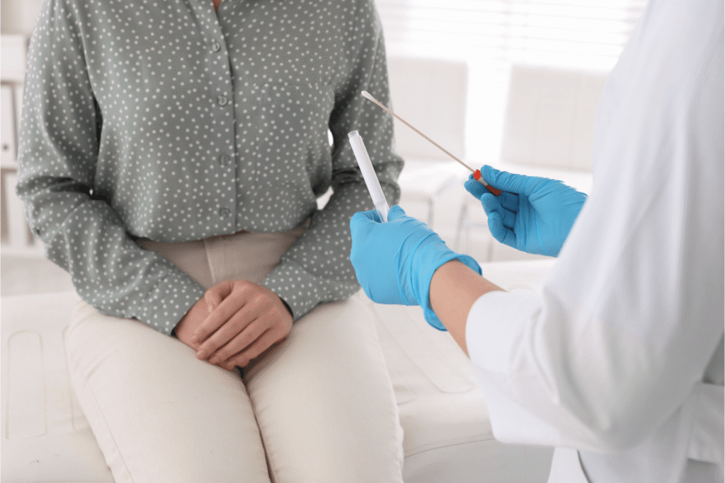 woman sitting on a doctors exam table as the doctor holds an STD testing kit