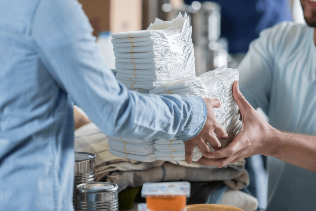 People exchanging a stack of baby diapers