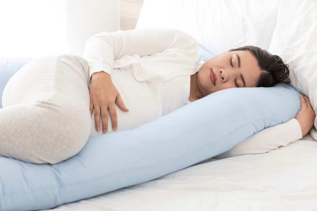 Pregnant woman sleeping with a body pillow