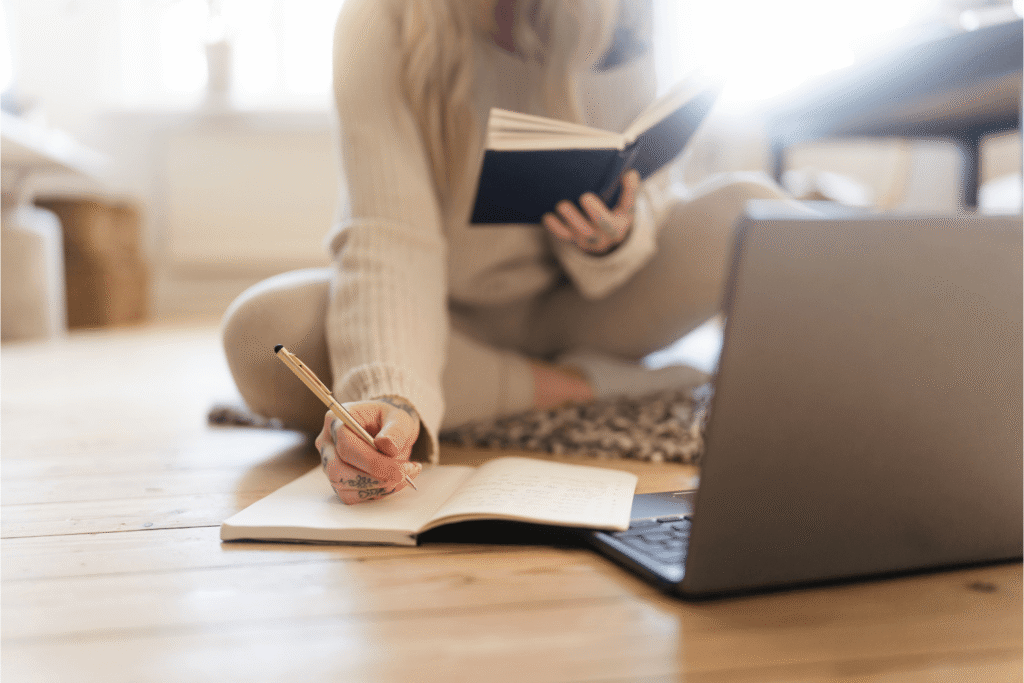 Woman sitting on a floor with her laptop and books open