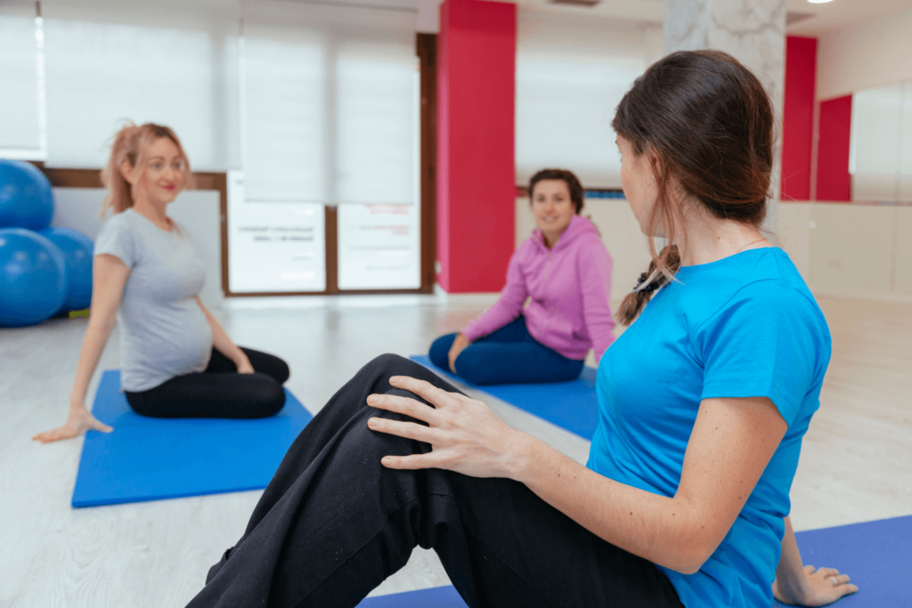 Pregnant woman sitting on a yoga mat in a class