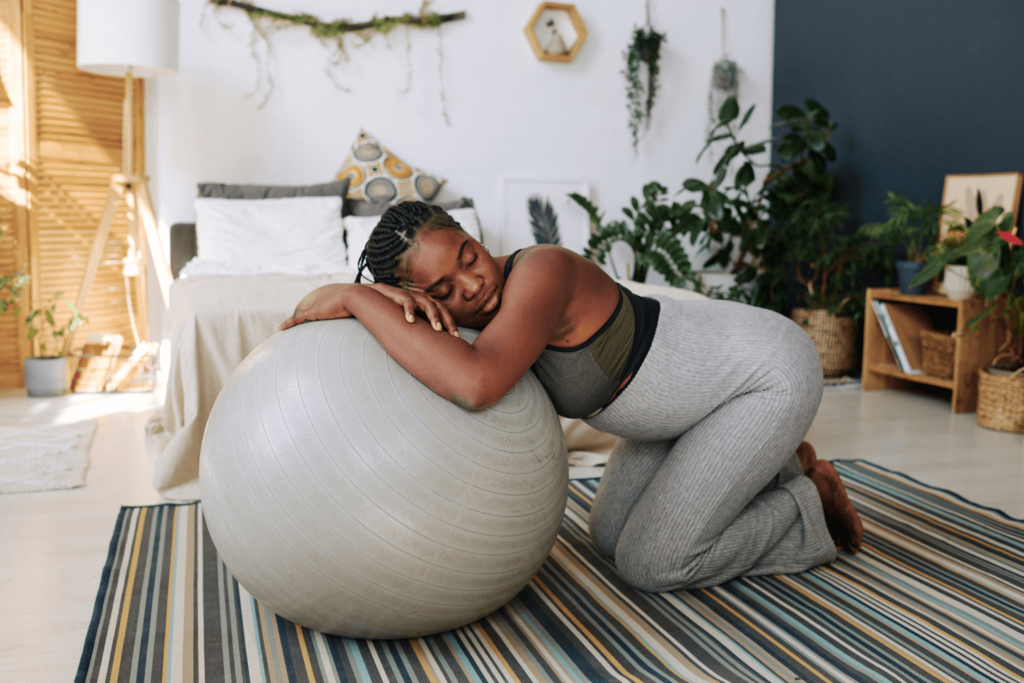 Pregnant woman resting against a medicine ball