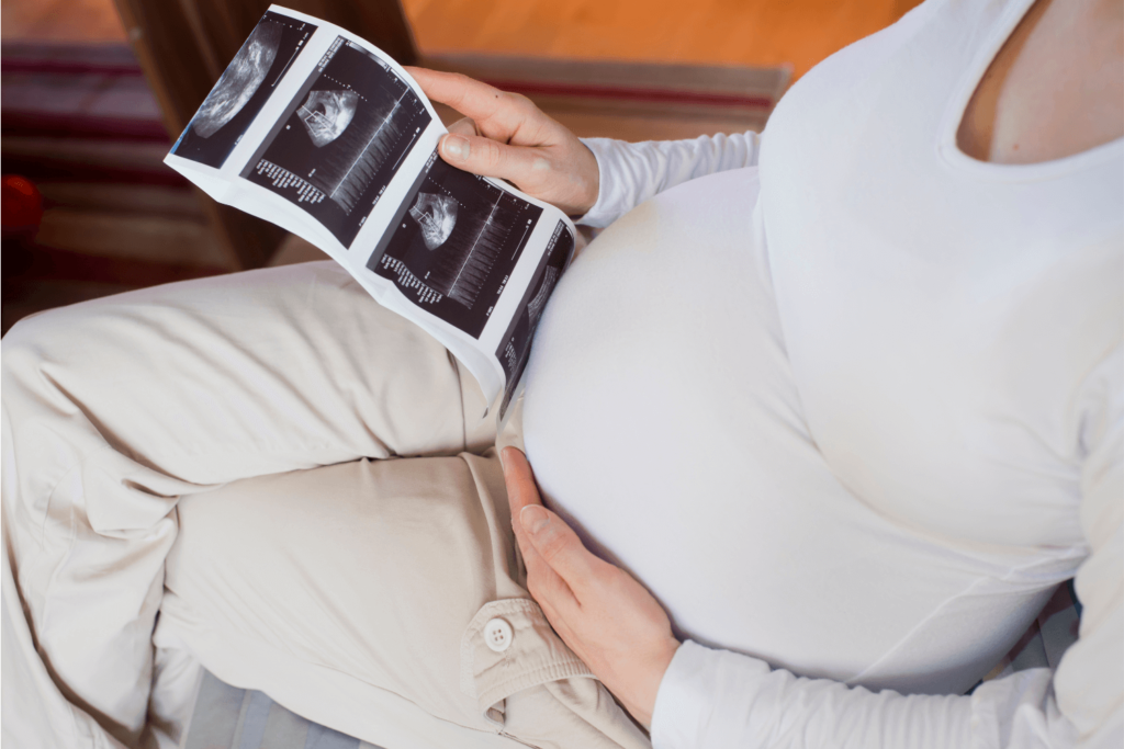 Pregnant mother holding ultrasound photos of her baby