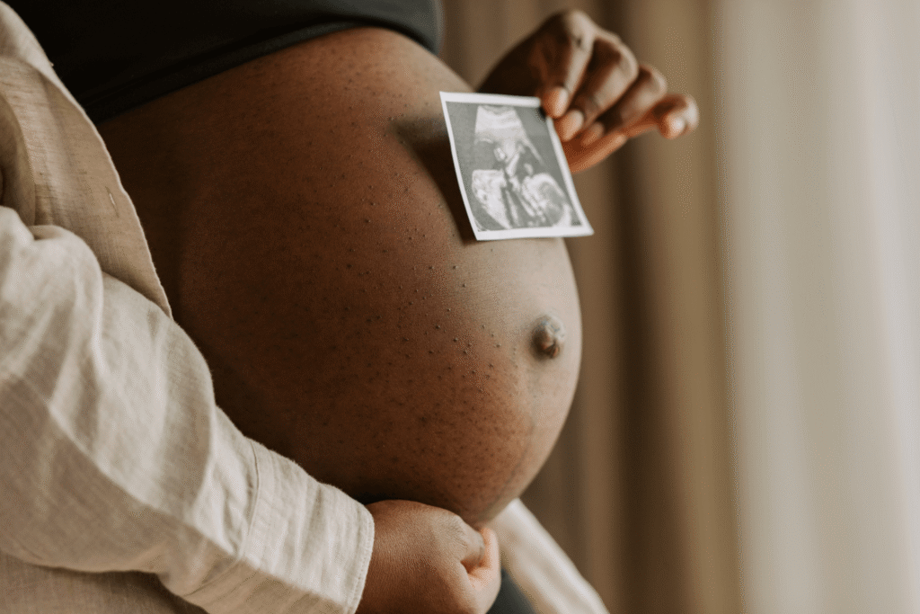 Pregnant woman holding ultrasound photo against her belly