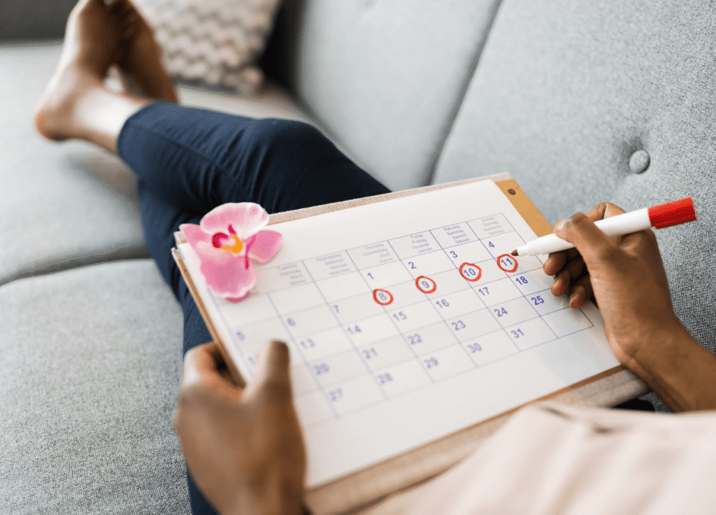 Woman sitting on a couch tracking her period using a calendar