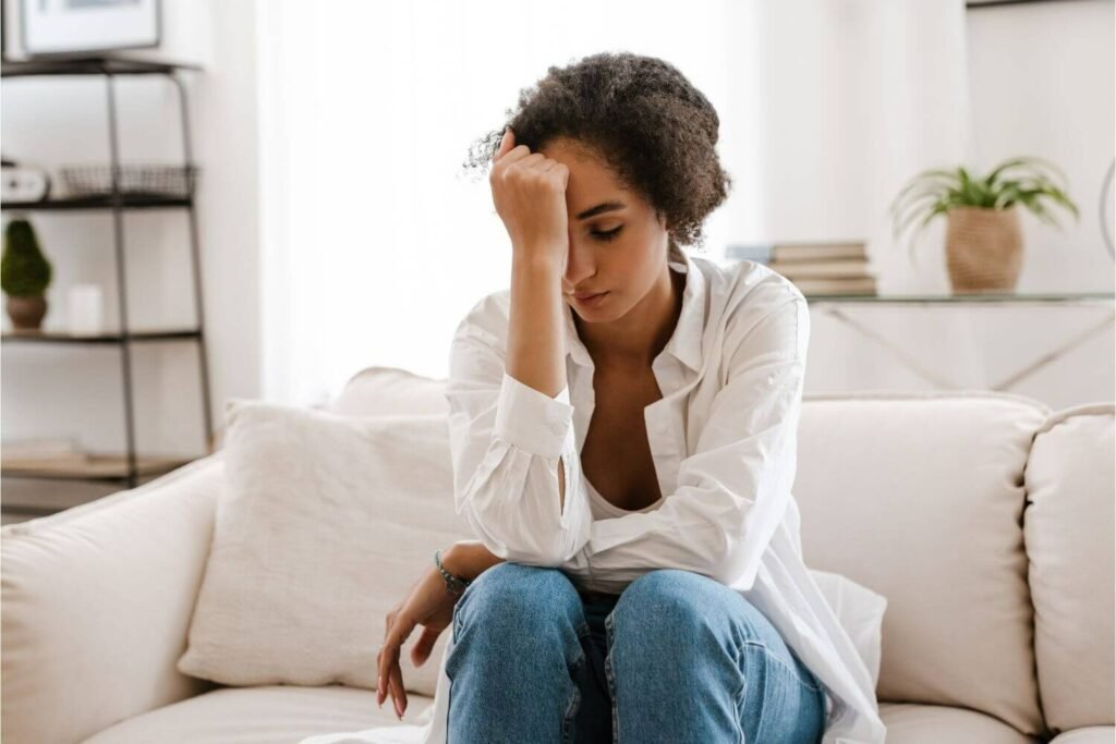 Upset woman sitting on a couch, holding her head in her hand