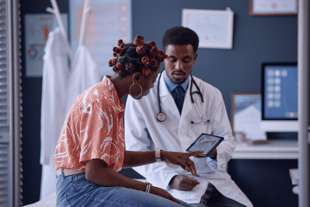 Woman sitting on an exam table at the gynecologist office as her doctor displays a diagram