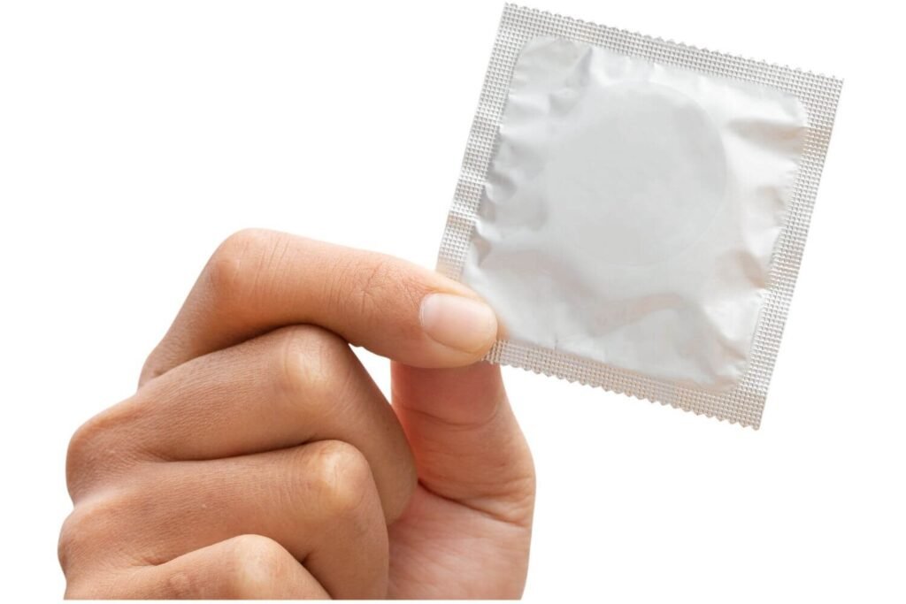 Hand holding a condom in a white wrapper