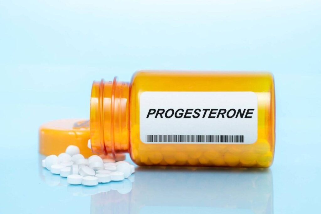 A bottle of progesterone pills is laying sideways, will small white pills coming out of the bottle