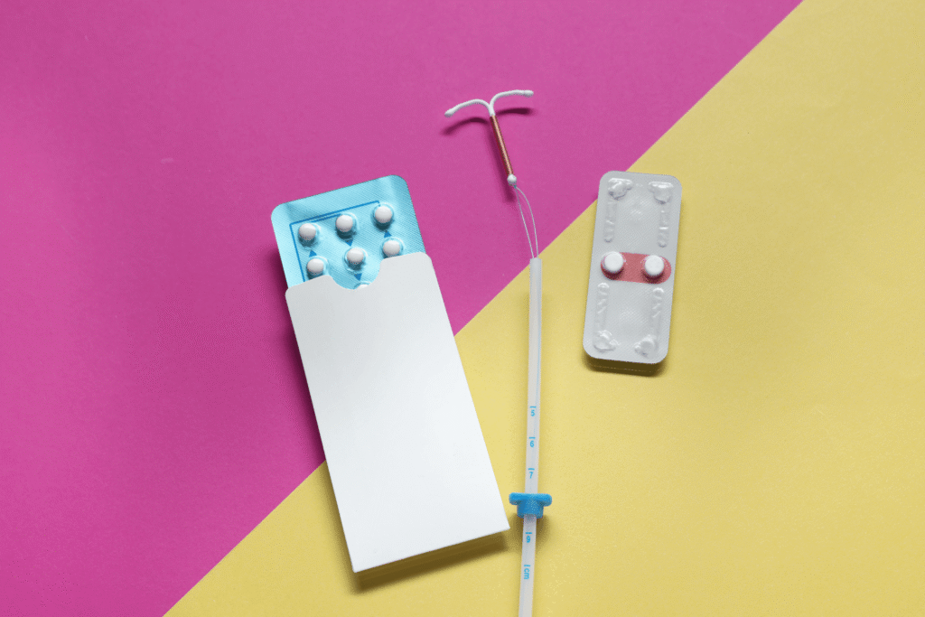 various types of birth control on a pink and yellow background
